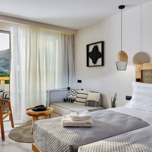 Junior suite with two single beds placed side by side, a sitting area and balcony access with garden view