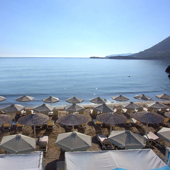 Panoramic view of a sandy beach with rows of sunbeds and umbrellas facing the sea