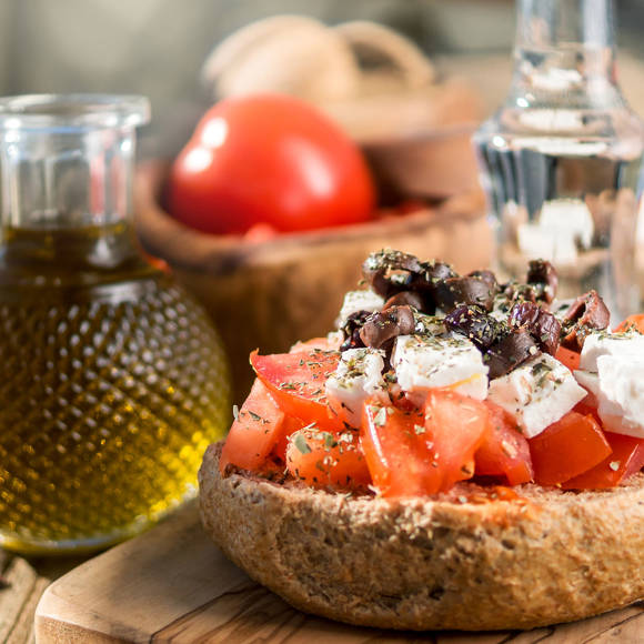 Close-up of traditional Cretan dakos with tomatoes, feta, olives, olive oil and raki