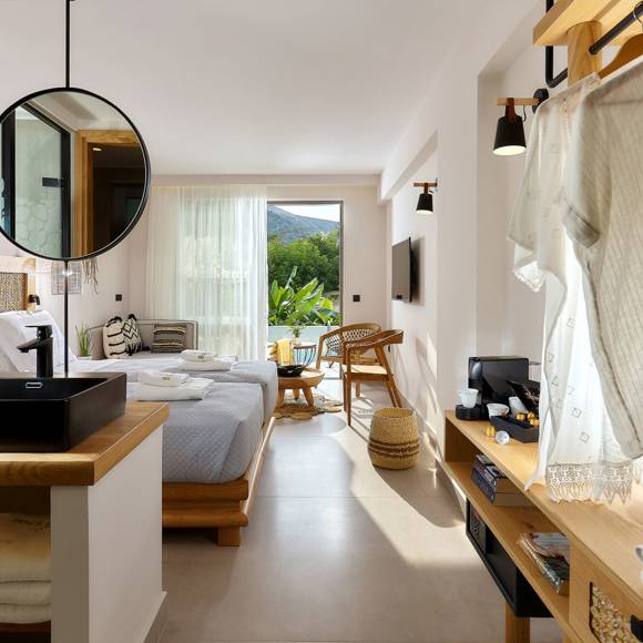 Junior suite with two single beds side by side, open vanity area, hanging area, wooden furniture and a balcony with garden view